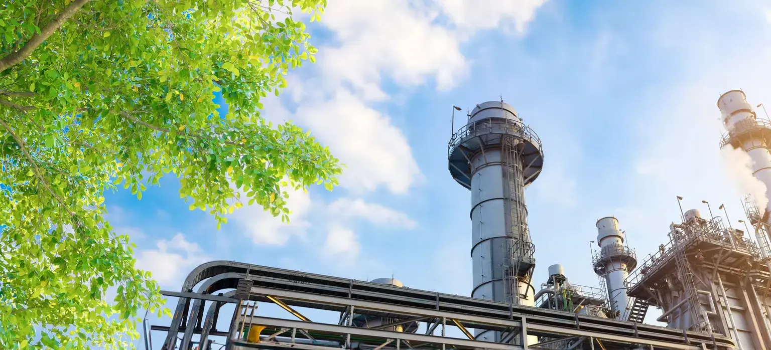 Industrial plant juxtaposed with vibrant greenery, symbolizing the balance of industry and eco-friendly energy practices.